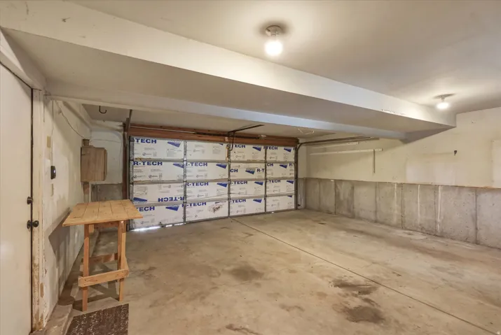 Spacious garage featuring a concrete floor, insulated garage door, and overhead lighting