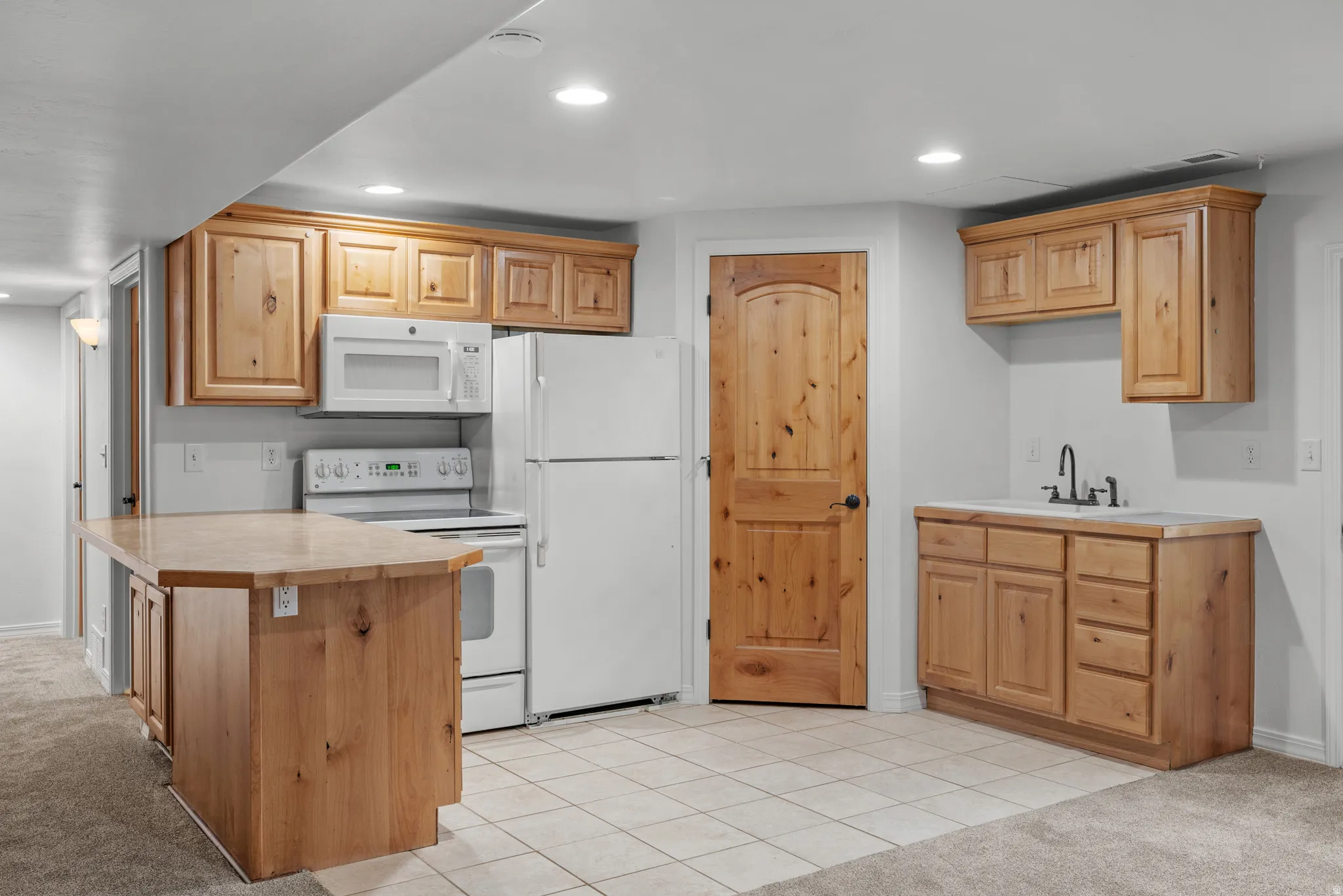Kitchenette featuring natural wood cabinetry, white appliances, recessed lighting, and tile flooring