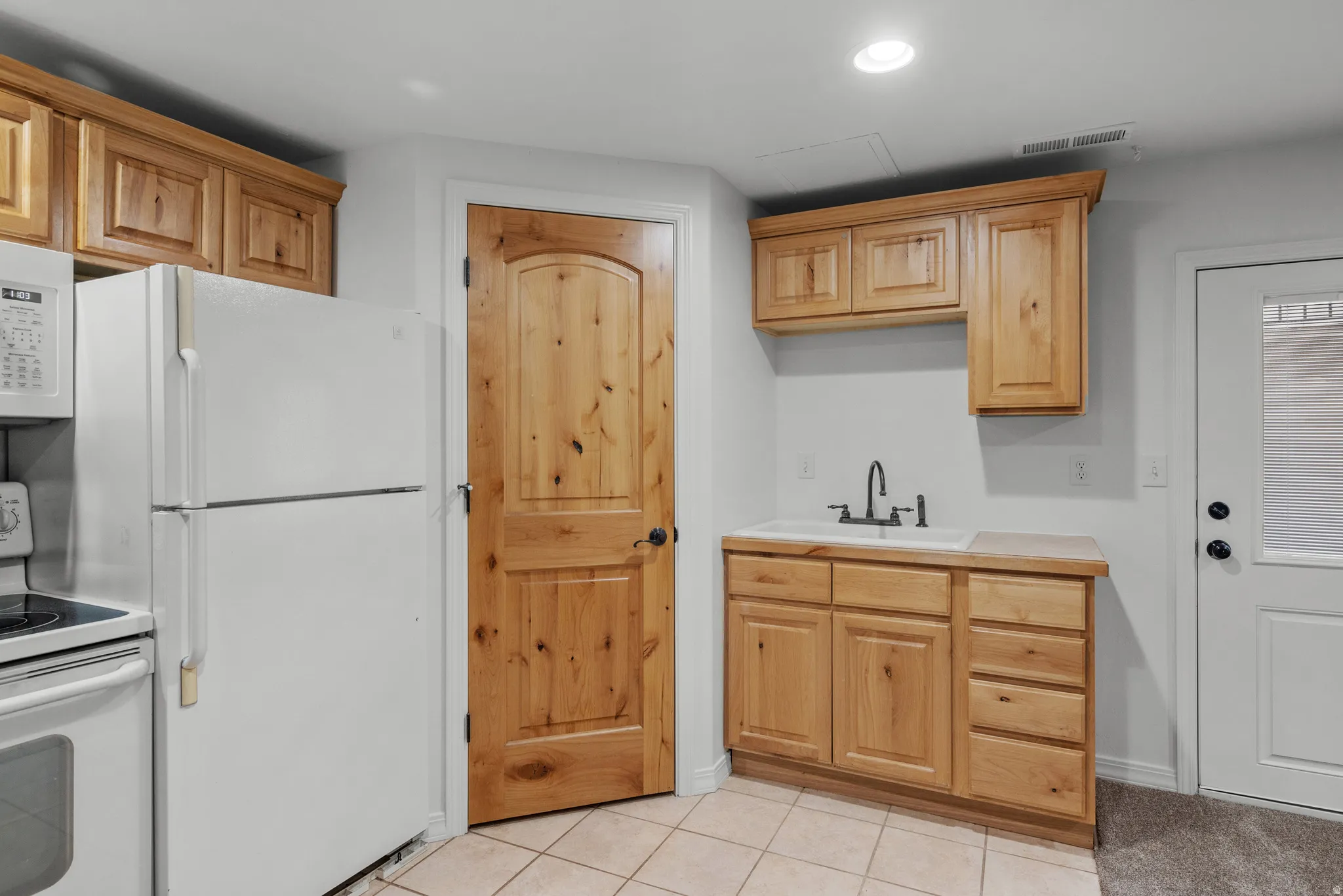 Kitchenette featuring wood-finish cabinetry and a white sink with a matte black faucet