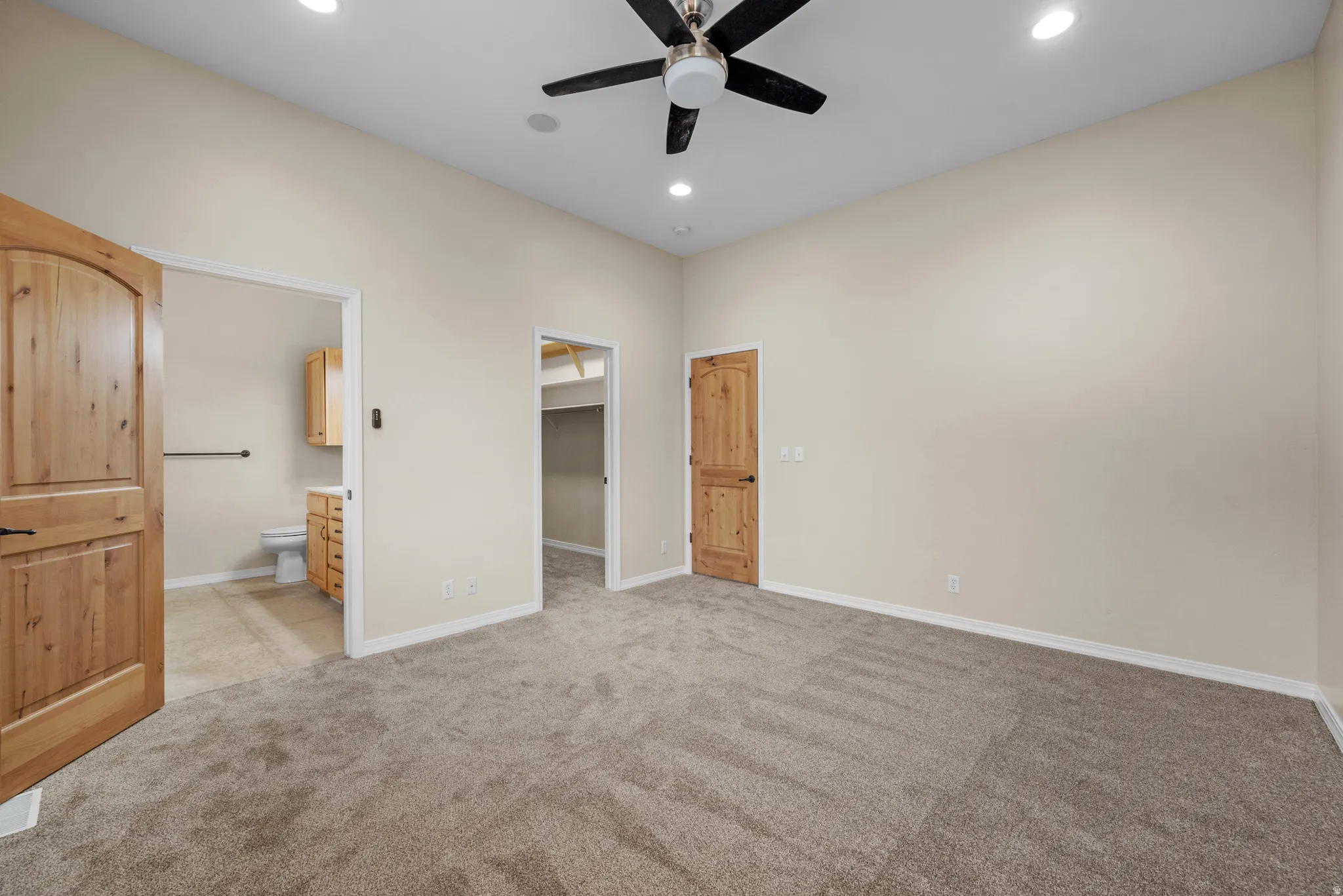 Spacious room featuring vaulted ceilings, recessed lighting, a ceiling fan, light-colored walls, and plush carpeting