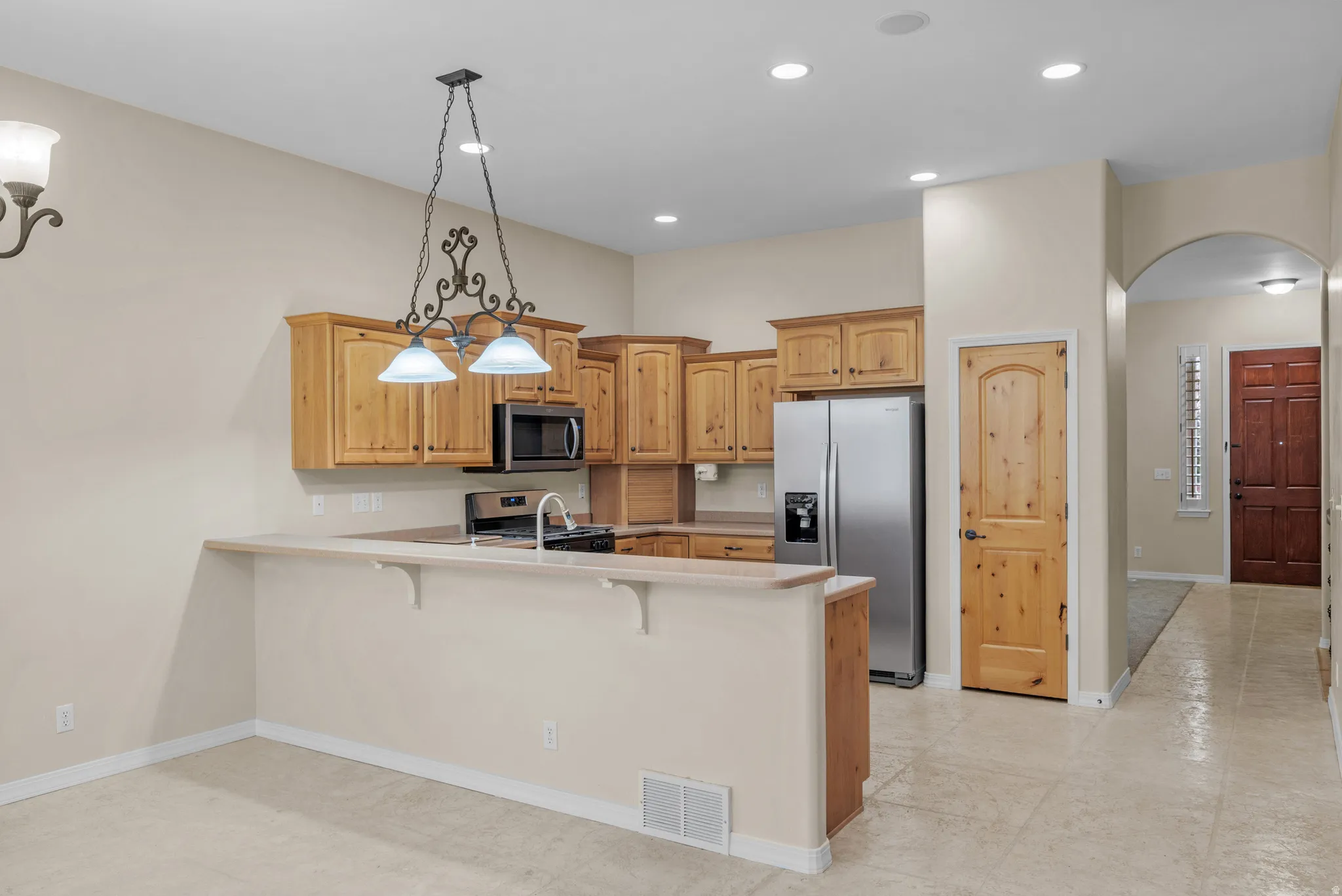 Kitchen featuring wood cabinetry, stainless steel appliances, and a breakfast bar with decorative pendant lighting