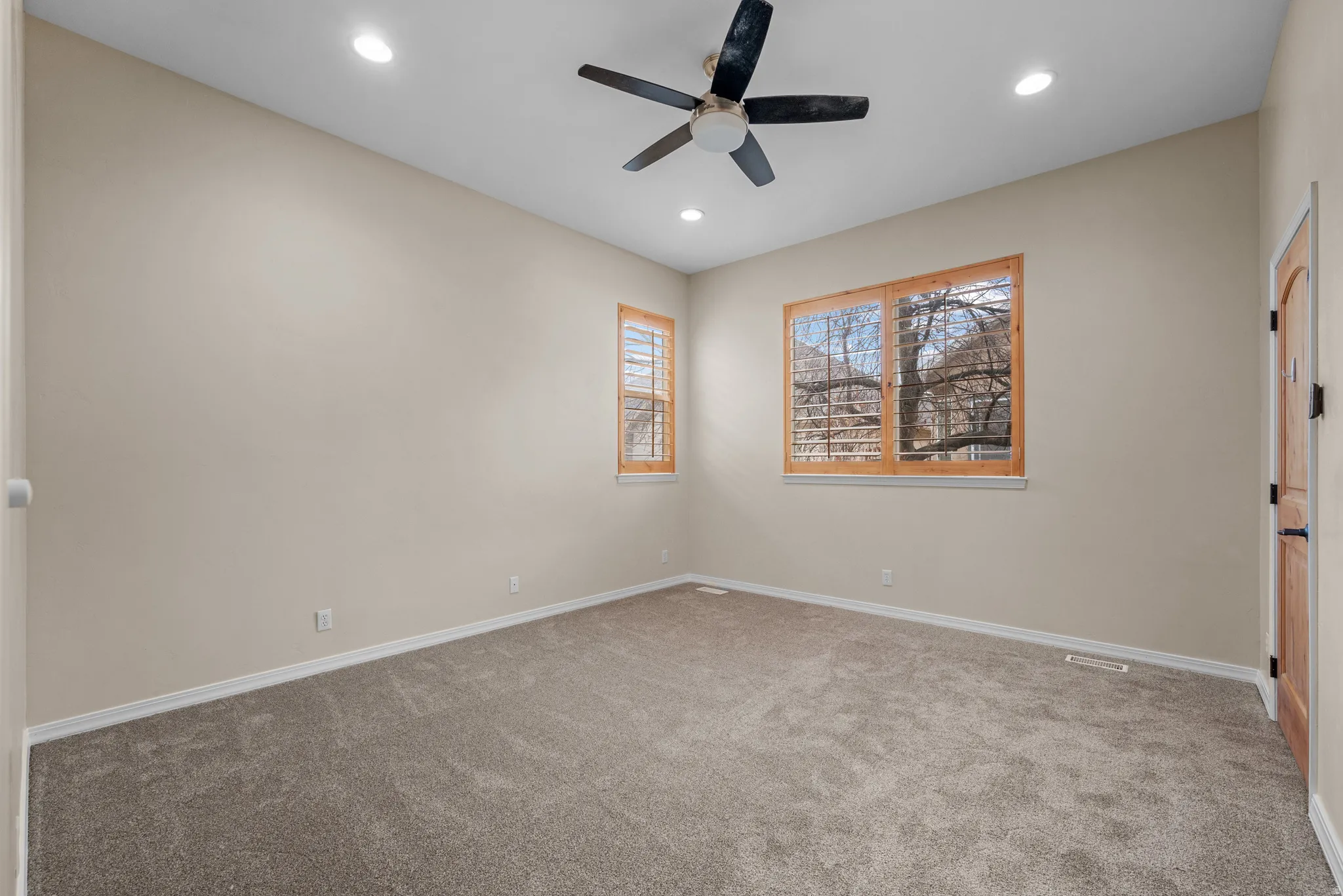 Room featuring vaulted ceilings, recessed lighting, wood-finish window frames with plantation shutters, a ceiling fan, and carpet flooring