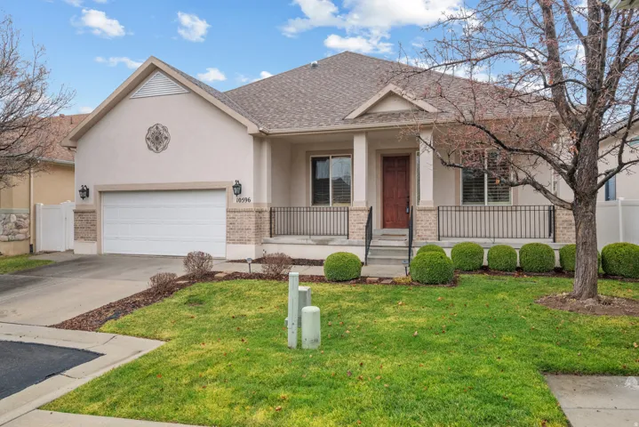 Stucco exterior with a two-car garage, covered porch, and mature landscaping