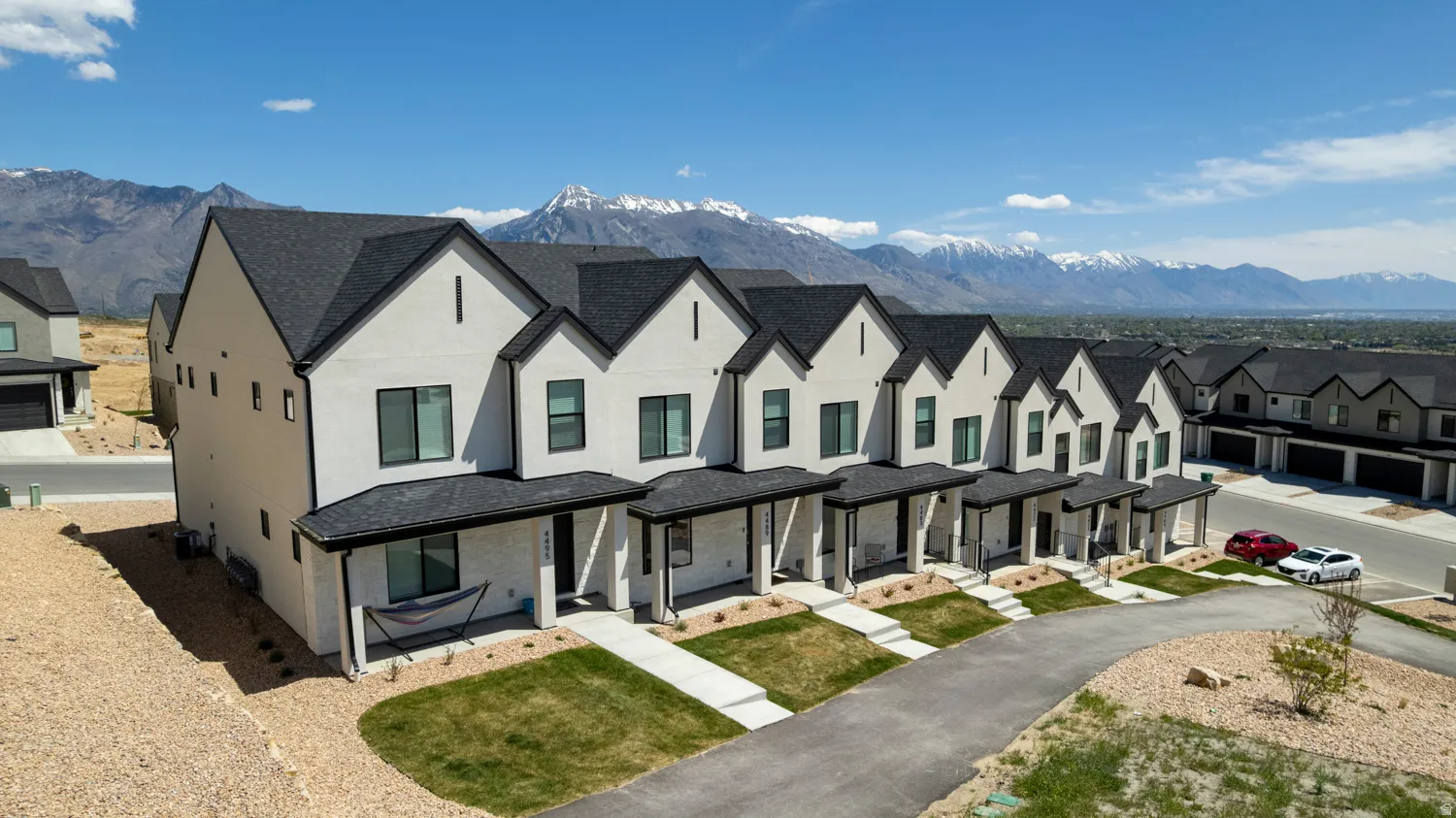 Modern townhome exterior featuring light-colored siding, dark-framed windows, and a contrasting dark roof