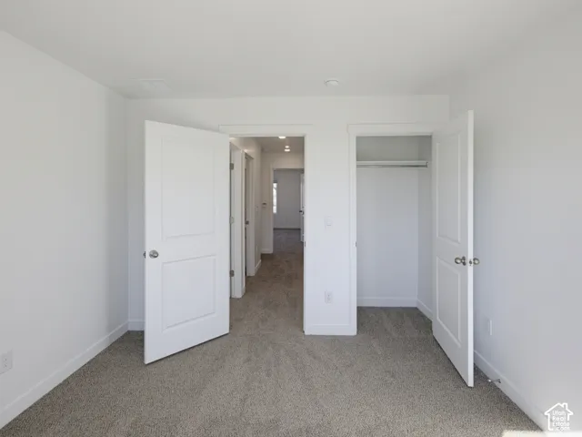 Wall-to-wall carpeting, bright white walls, and a built-in closet with hanging rod