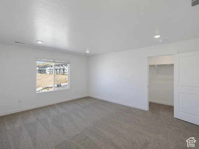 Recessed lighting, neutral-toned carpeting, white walls, and a window with blinds