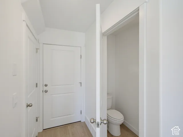 White interior doors with panel detailing, light wood-finish flooring, and a white toilet