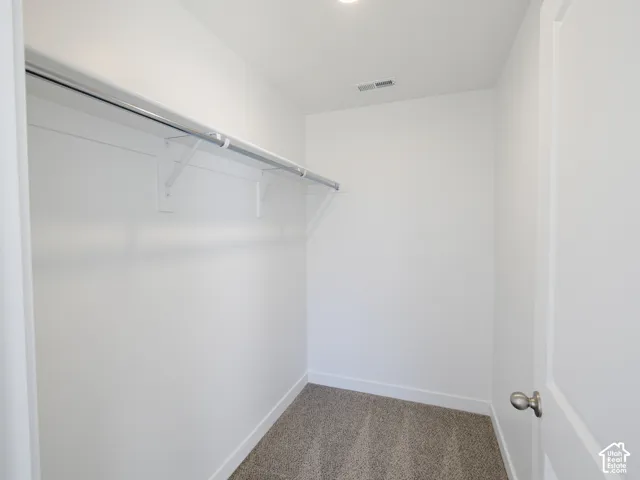 Built-in wire shelving with hanging rod, carpeted flooring, and recessed ceiling lighting