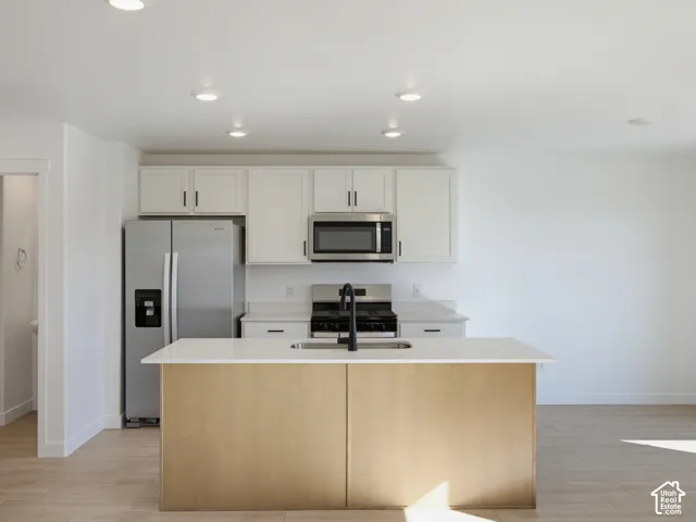 Kitchen featuring white cabinetry, stainless steel appliances, a center island with a sink, and recessed lighting
