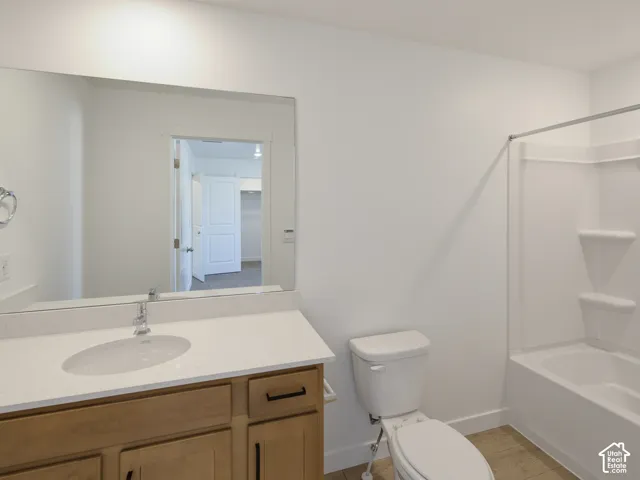 Light wood-finish vanity with a single basin sink, white countertop, and chrome faucet