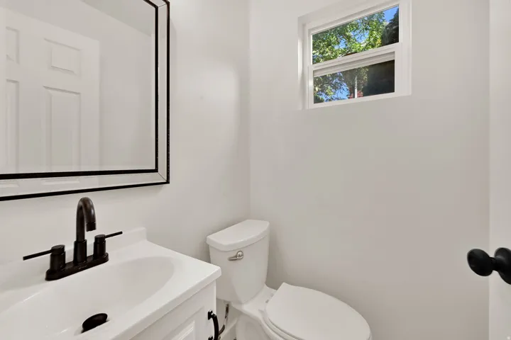 Bathroom featuring a white vanity with an integrated sink, matte black faucet, and a rectangular mirror with a black frame