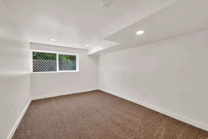 Carpeted room featuring a white window frame, recessed lighting, and white baseboards