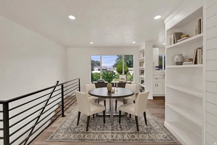 Open-concept living space with recessed lighting, light wood-finish flooring, and a modern black metal railing