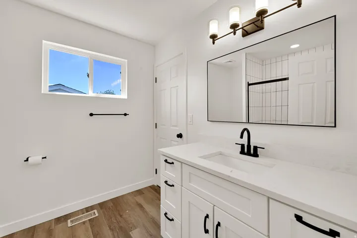 Bathroom featuring a white vanity with integrated sink, black fixtures, and a large framed mirror