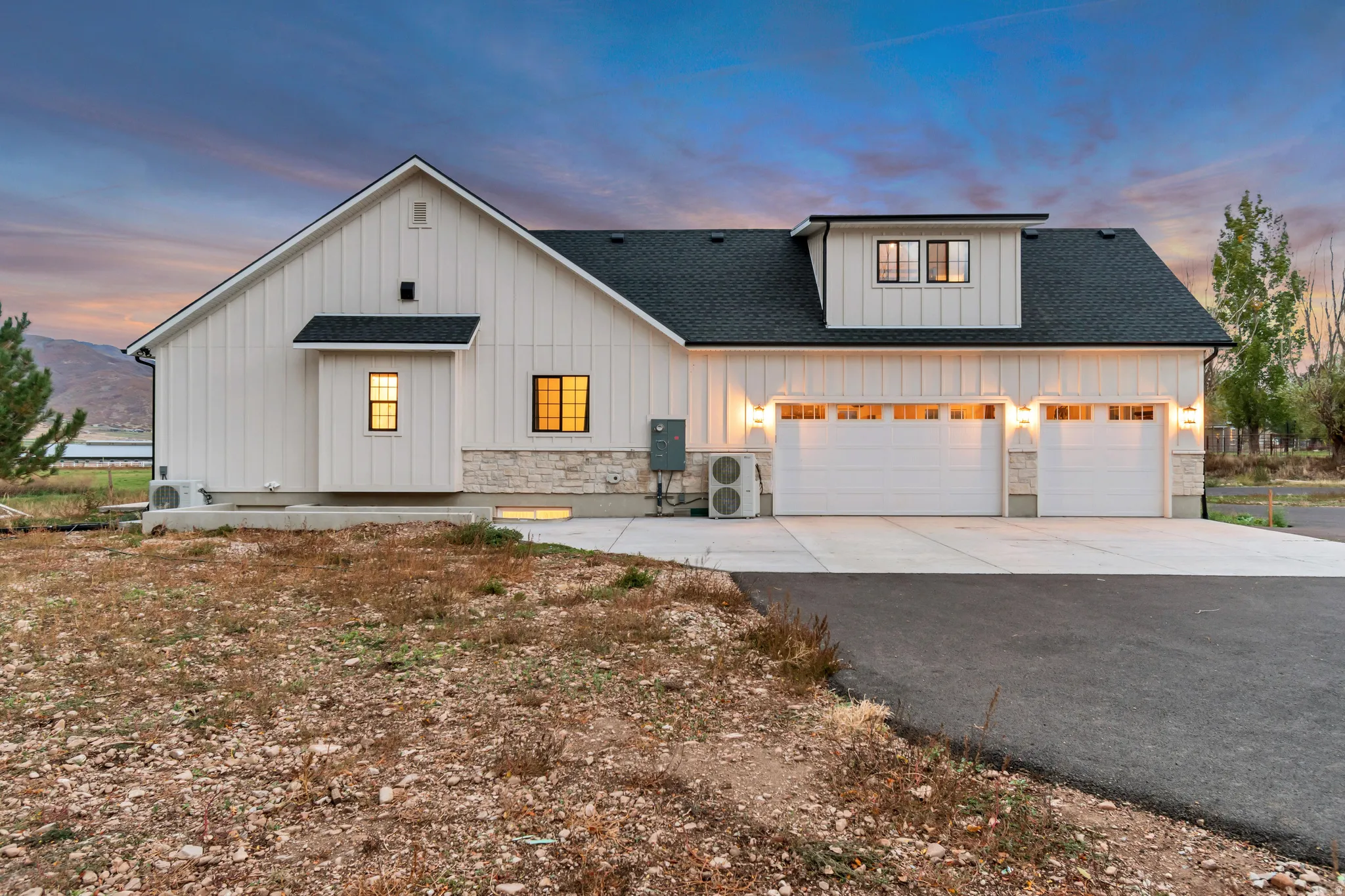 Modern farmhouse exterior featuring vertical white siding and a stone veneer foundation
