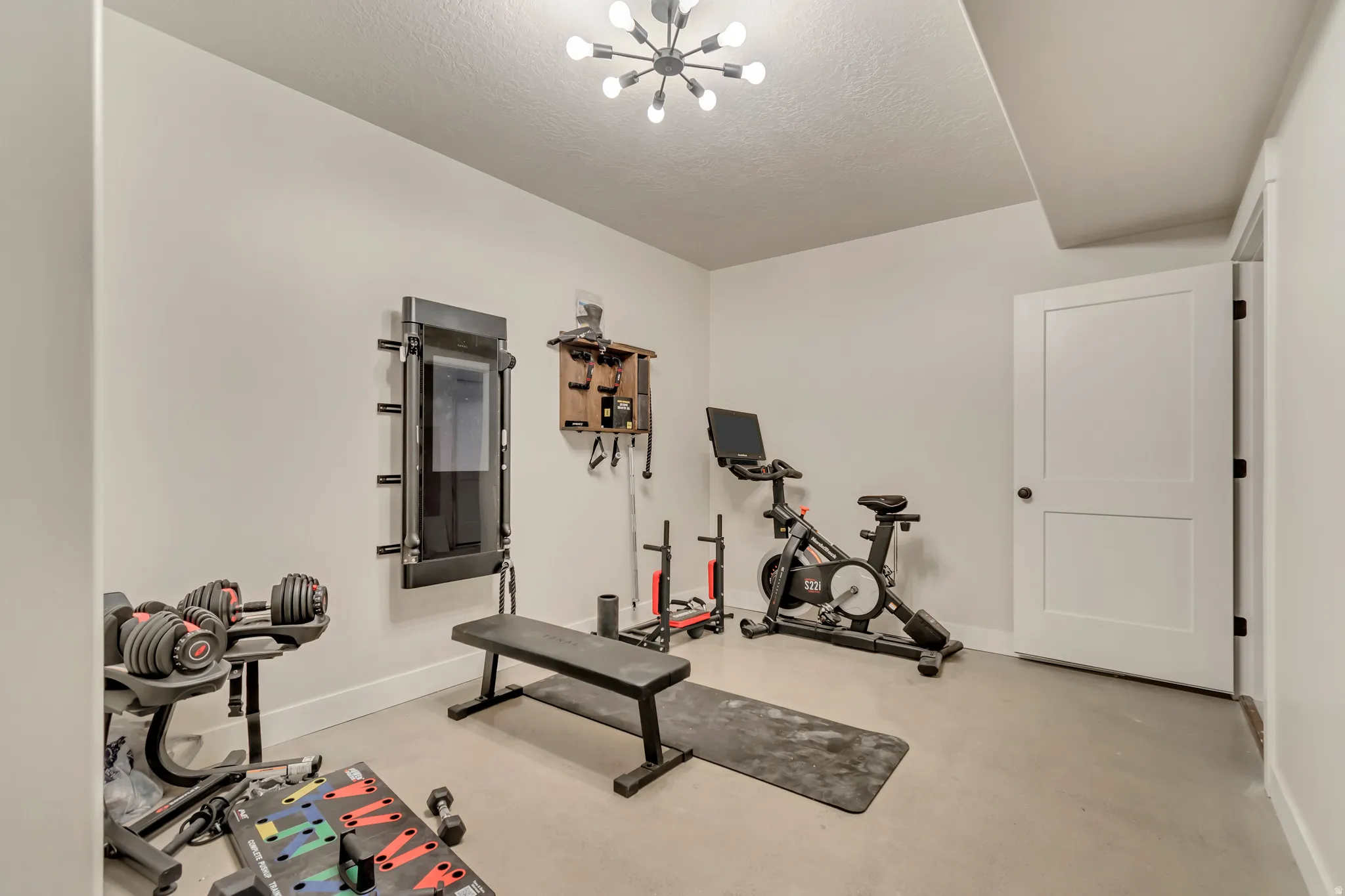 Dedicated exercise space featuring light-toned walls and a modern ceiling fixture