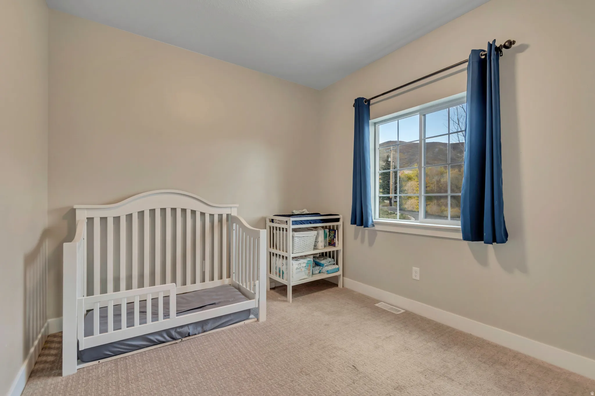 Carpeted room with a large window, offering a mountain backdrop