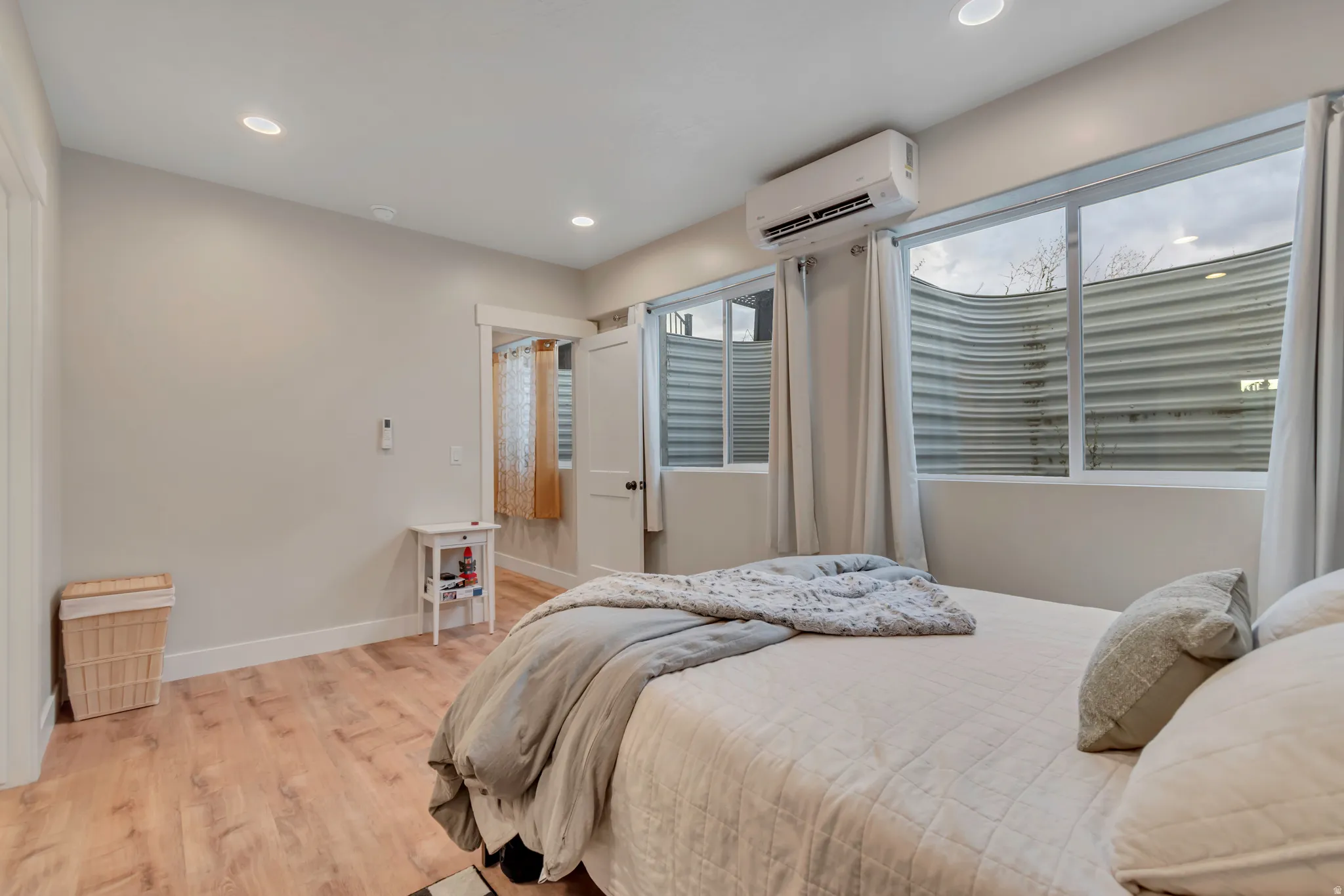 Interior room with light wood-finish flooring, recessed ceiling lighting, and a wall-mounted air conditioning unit