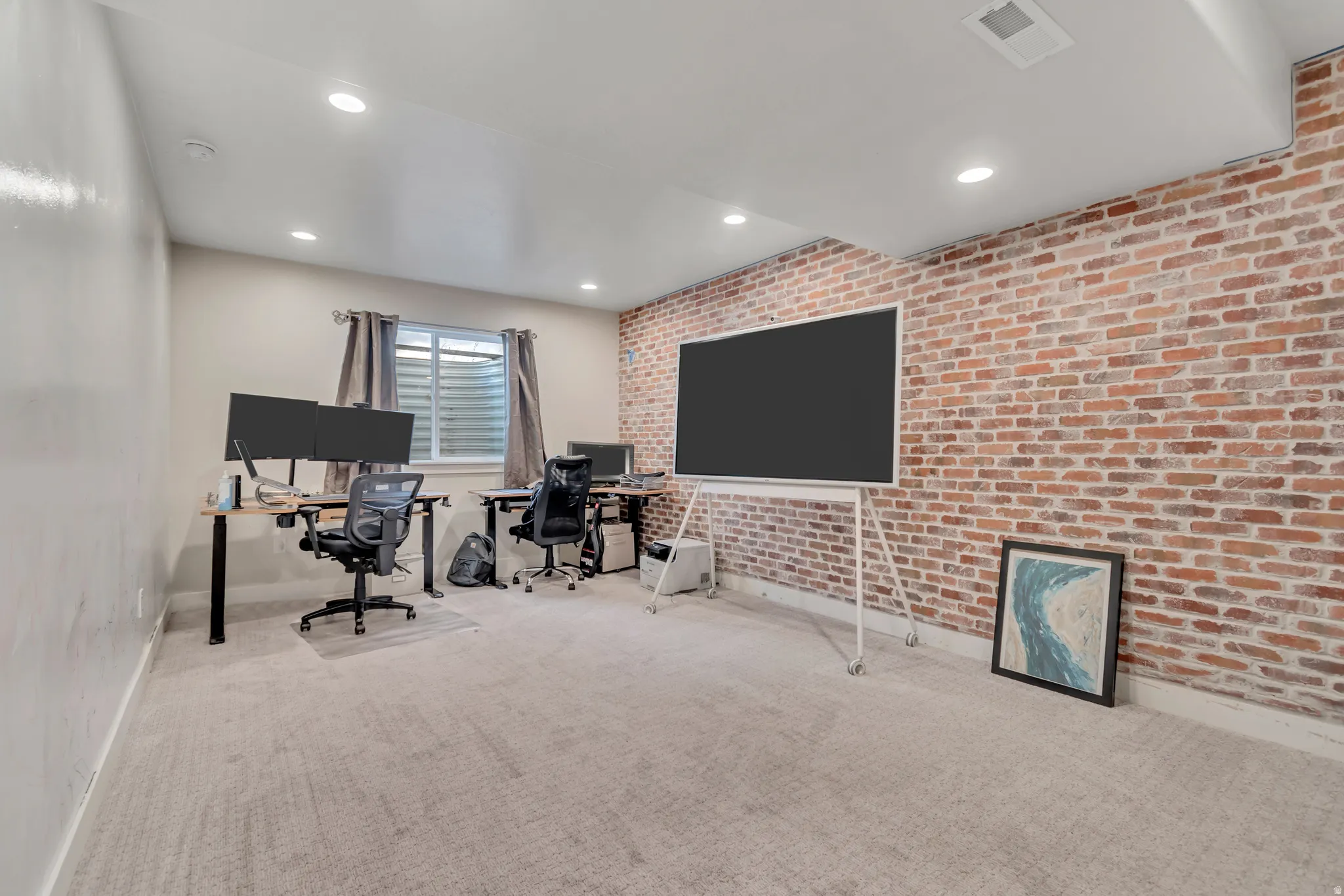 Spacious room featuring a brick accent wall, recessed lighting, and light-toned carpeting