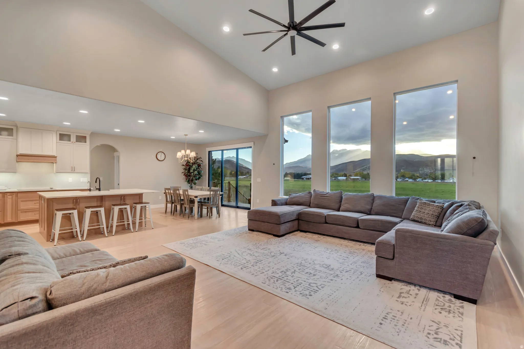 Open-concept living space featuring high vaulted ceilings, light wood-finish flooring, and a modern ceiling fan