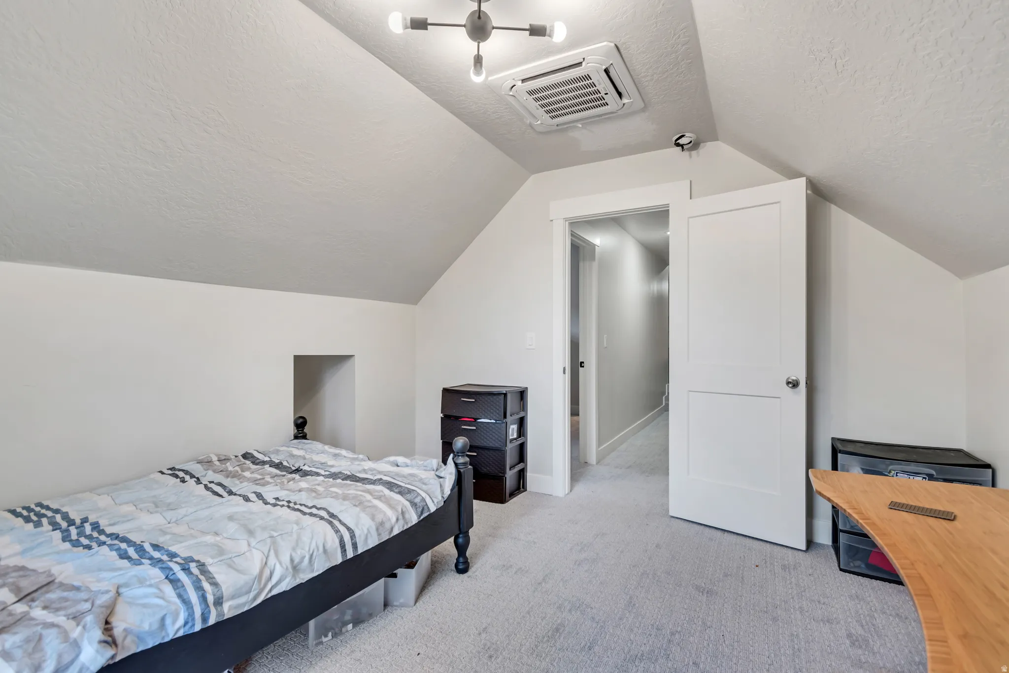 Room featuring sloped ceilings, light gray carpeting, and a built-in wall niche