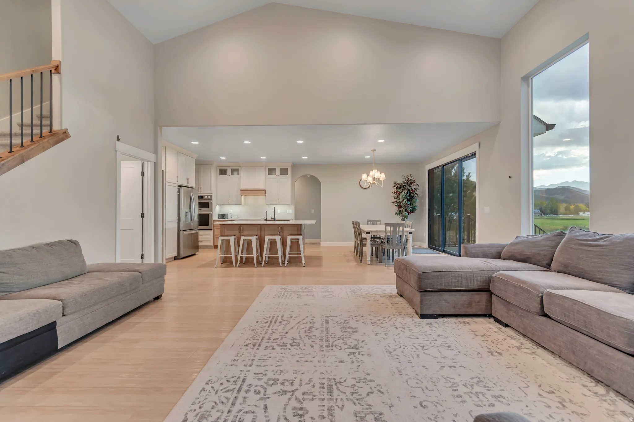 Vaulted ceilings highlight this open-concept living space with light wood-finish flooring