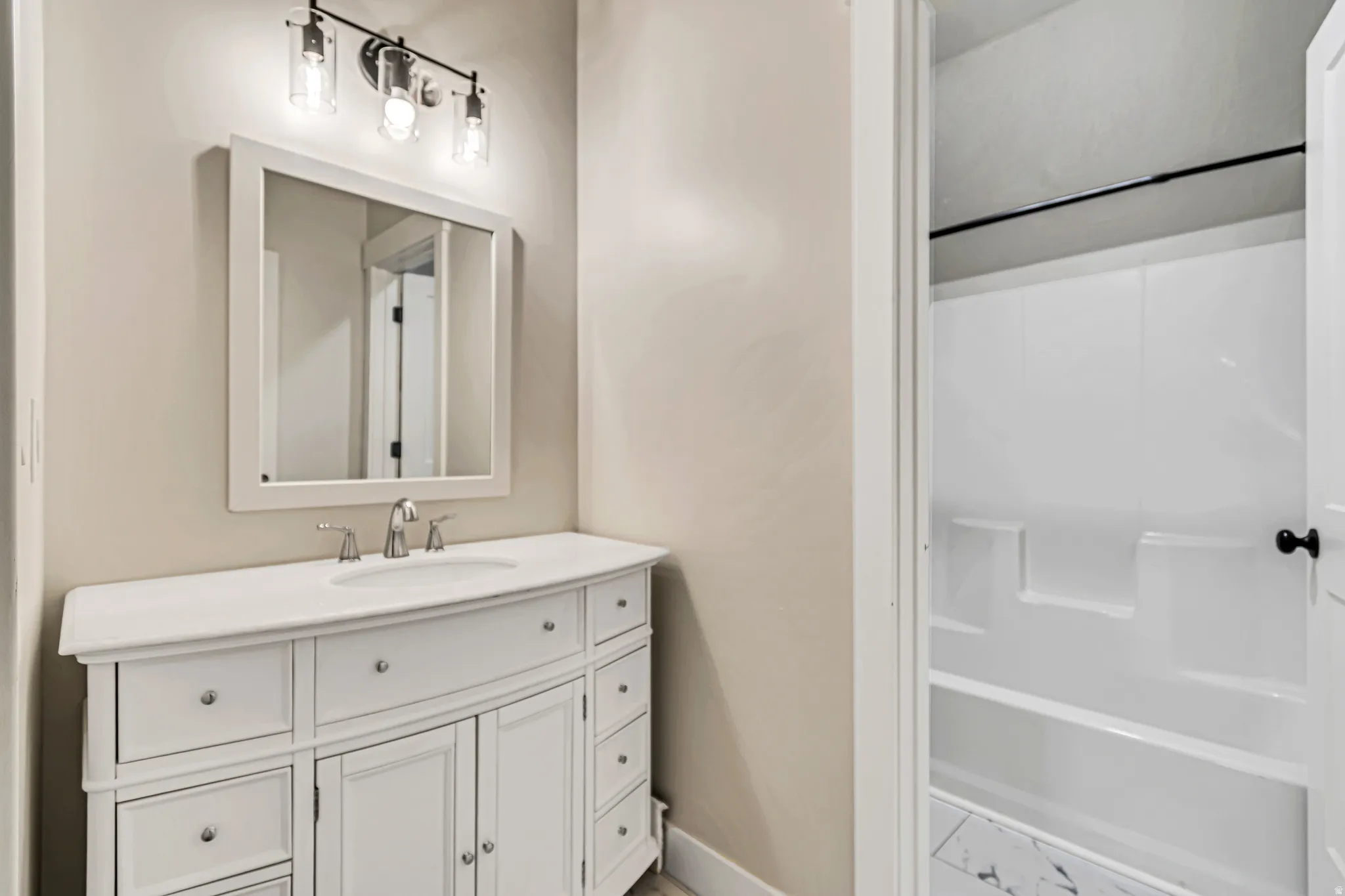 Bathroom featuring a white vanity with an integrated sink, polished chrome faucet, and a framed mirror
