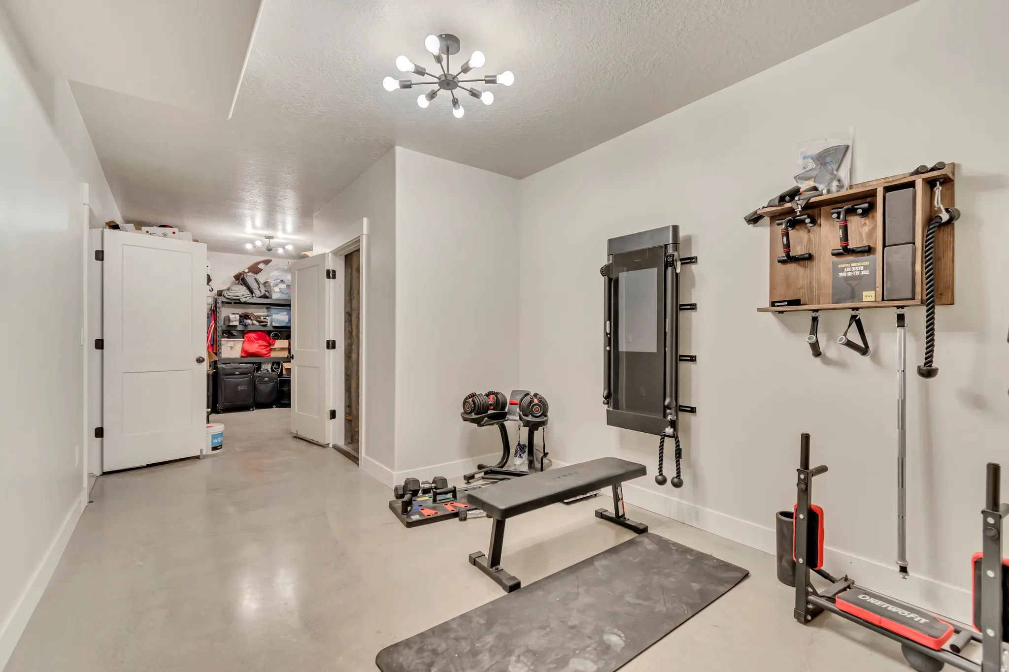 Versatile room featuring light grey flooring, white walls, and a modern sputnik-style ceiling light