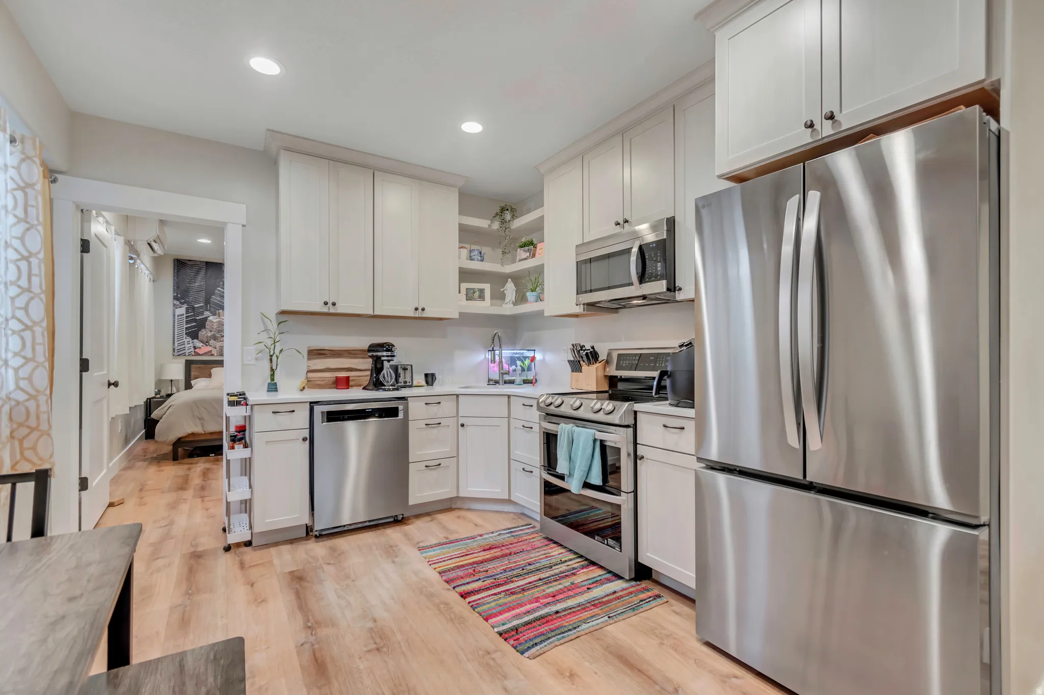 Modern kitchen featuring white cabinetry, stainless steel appliances, light wood-finish flooring, and recessed lighting