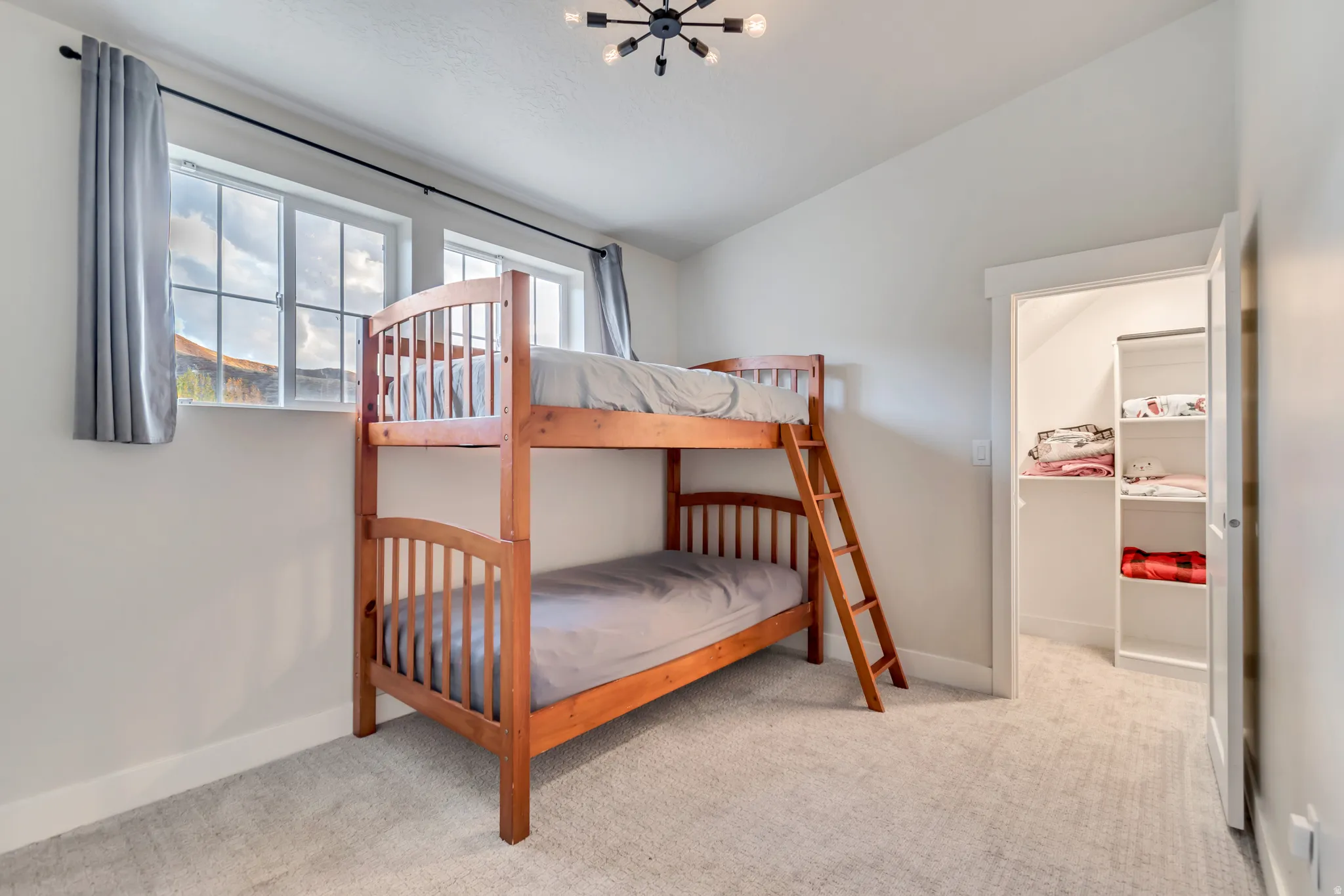 Bright room featuring a multi-pane window, neutral-toned carpeting, and a built-in closet with shelving