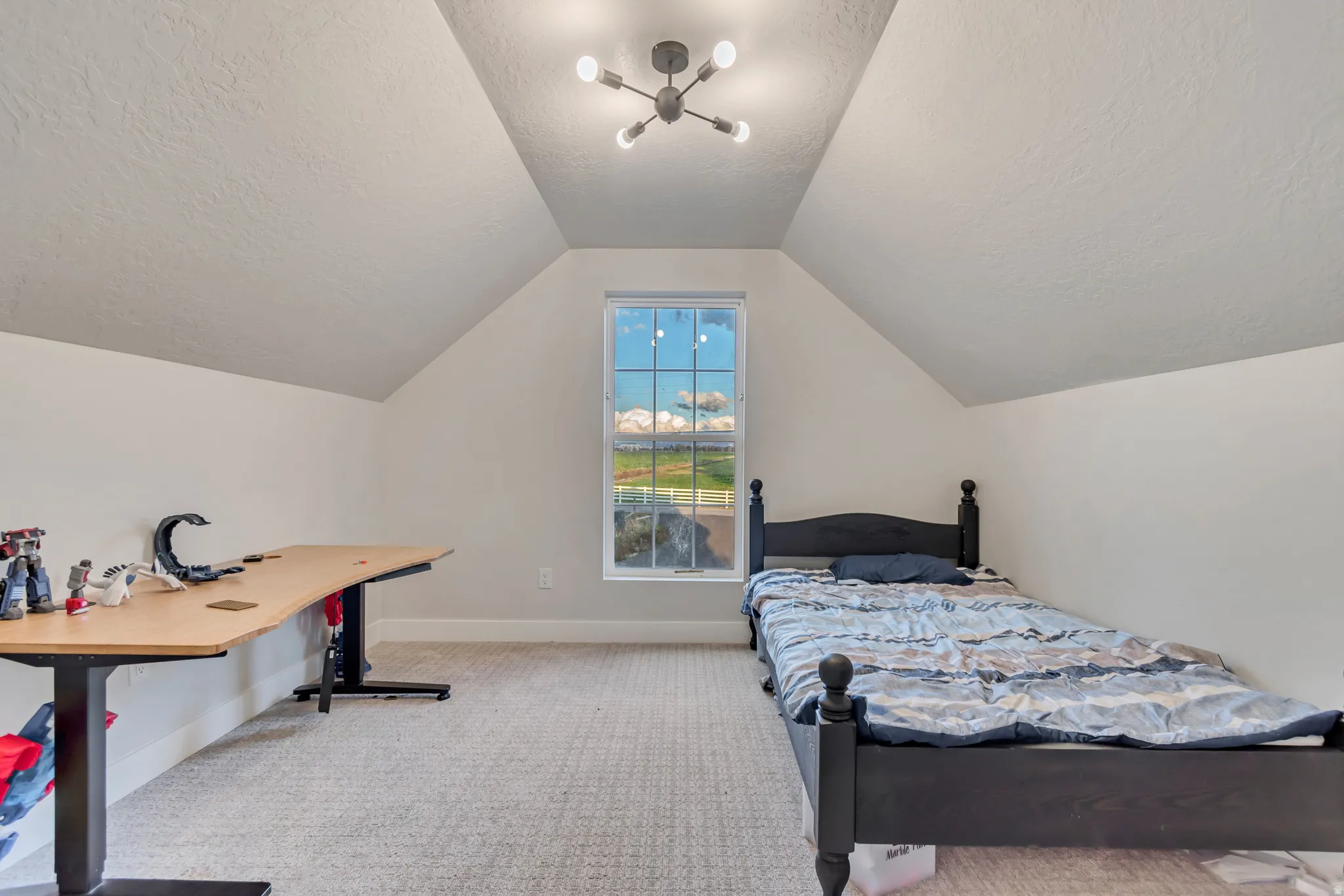 Spacious room featuring sloped ceilings, a large window, light-toned carpet, and a modern ceiling light fixture