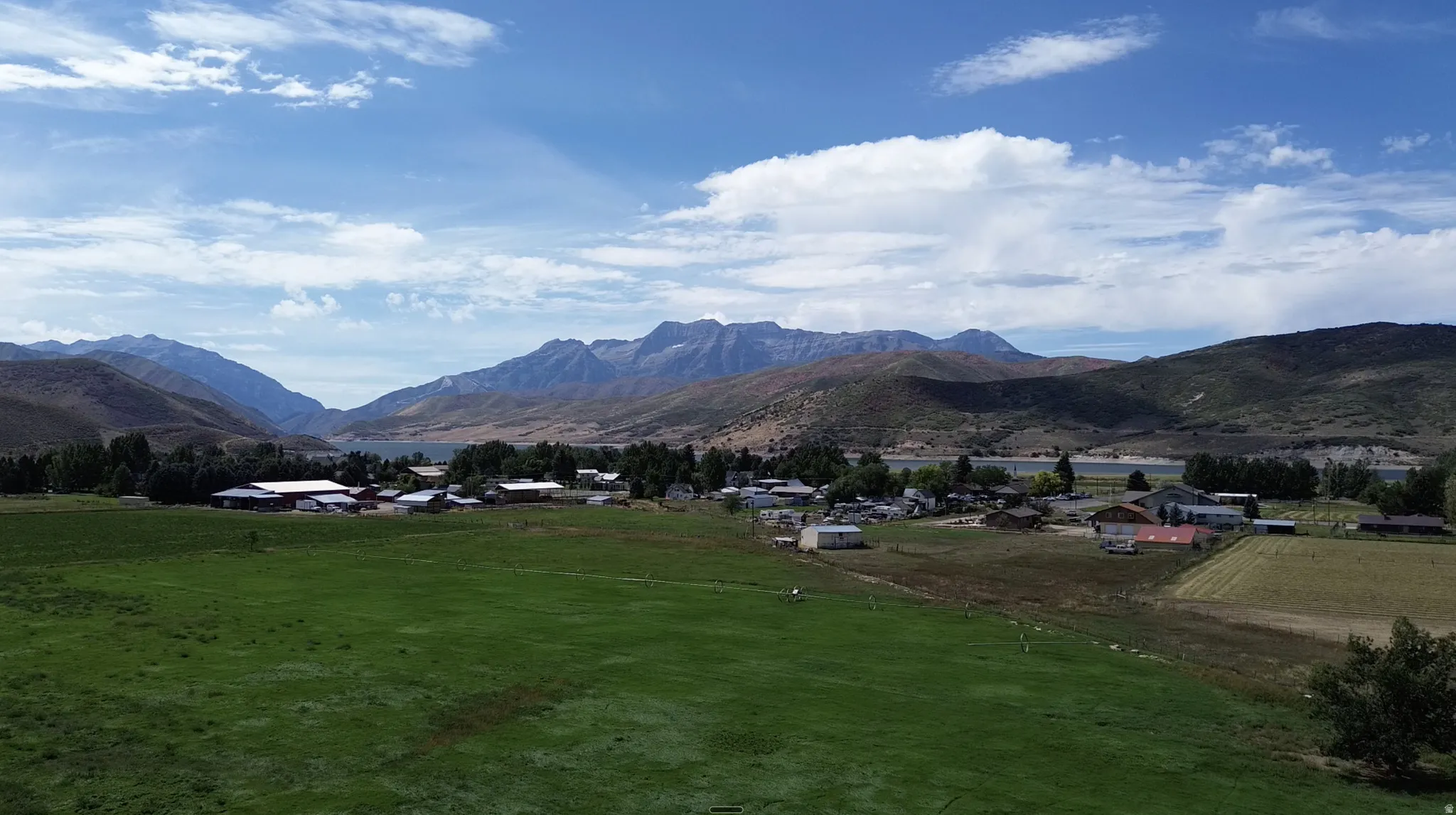Expansive green field with distant mountain ranges and a body of water
