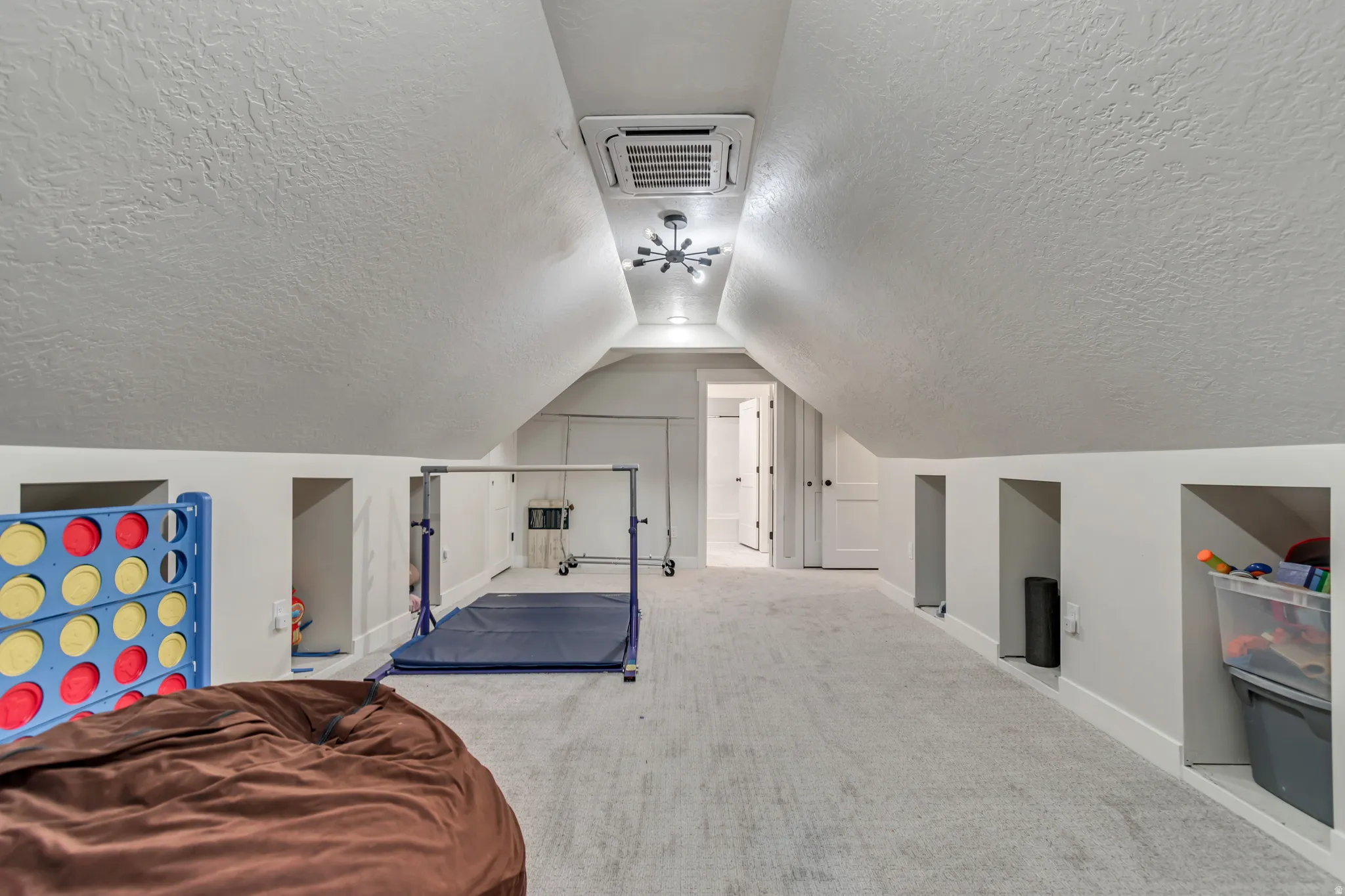 Carpeted bonus room featuring sloped ceilings, recessed wall storage, and a ceiling-mounted lighting fixture