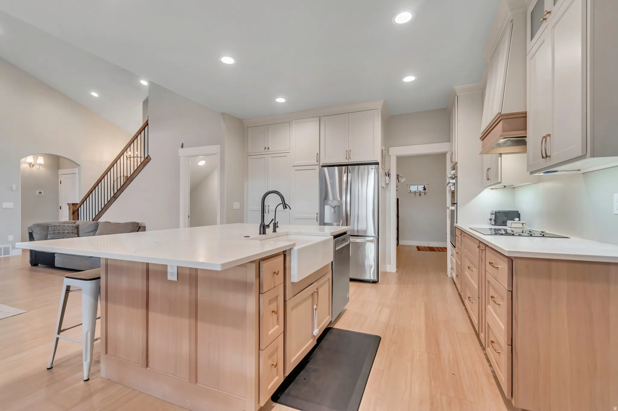 Kitchen featuring a large central island with seating, white farmhouse sink, and black gooseneck faucet