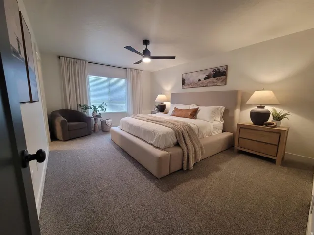 Carpeted room featuring a ceiling fan, window with horizontal blinds, and window drapes