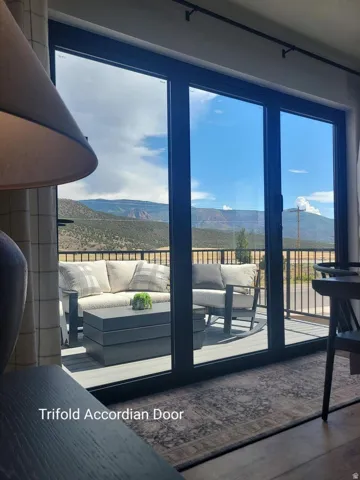 Trifold accordion door opening to an outdoor deck featuring composite decking and a black metal railing
