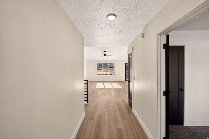 Hallway featuring wood-finish flooring, light-toned walls, and a textured ceiling