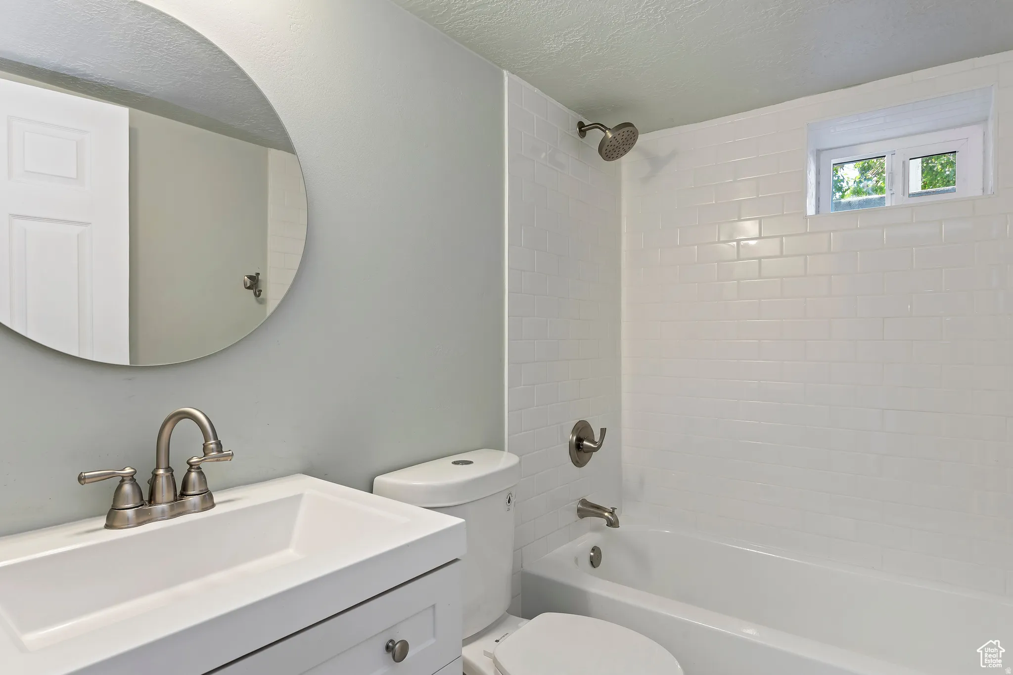 Bathroom featuring white subway tile surround, built-in bathtub, and a window for natural light