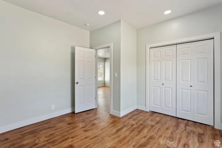 Bedroom featuring wood-finish flooring, recessed lighting, and a double bi-fold closet