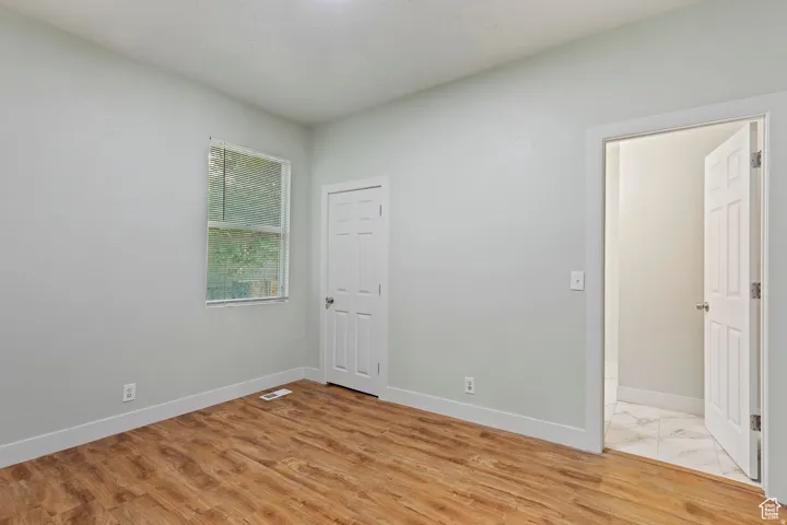Interior space with wood-finish flooring, light-colored walls, a single window, and a paneled door