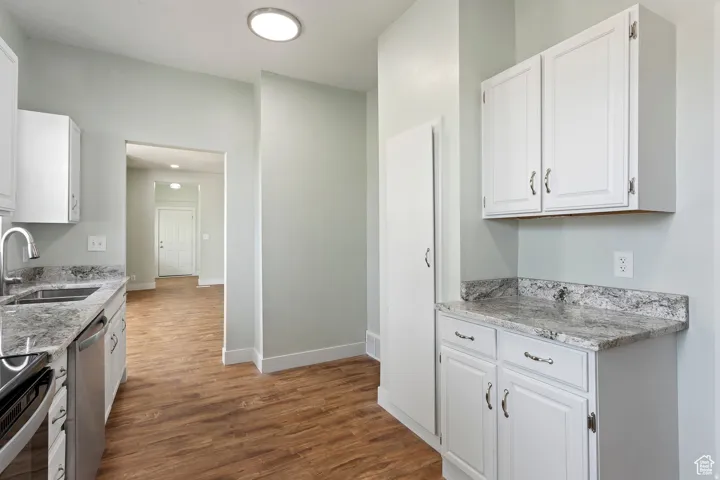 Kitchen featuring wood-finish flooring, white cabinetry, and light-toned countertops