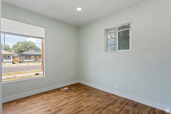 Room featuring two windows with white trim, wood-finish flooring, and light-colored walls