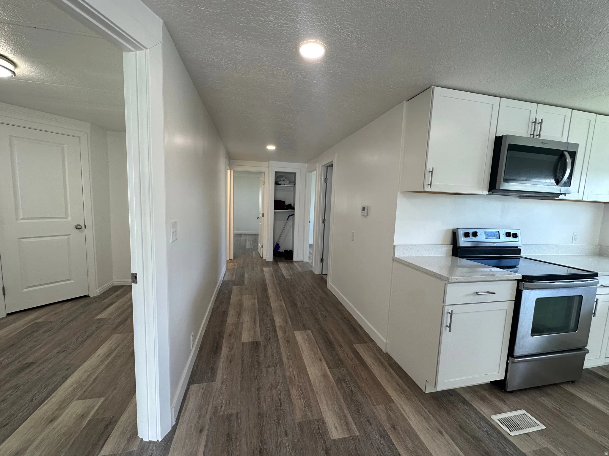 Kitchen space featuring white cabinetry, stainless steel appliances, and a light-colored countertop