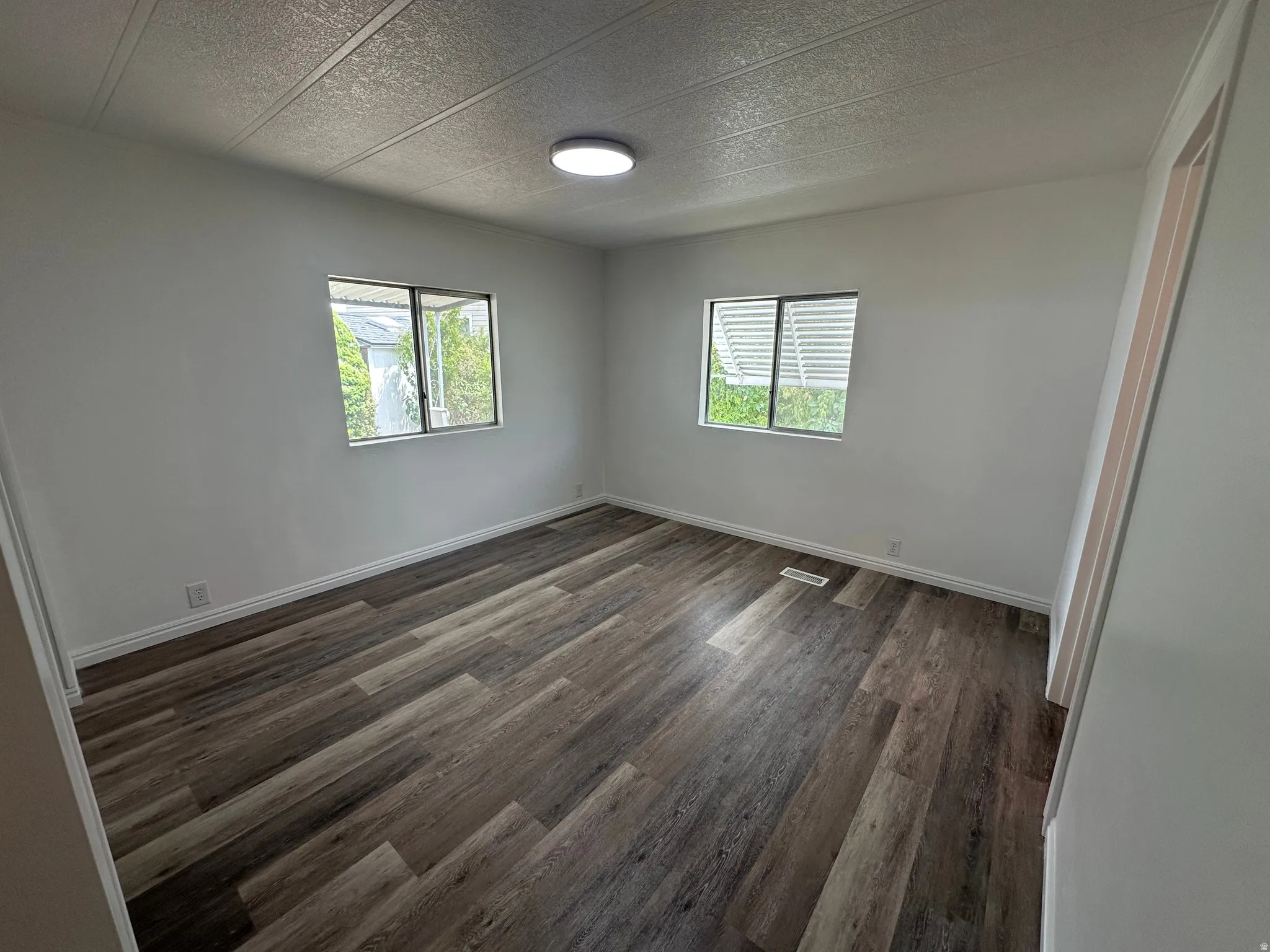 Room featuring wood-finish flooring, white walls, and two windows