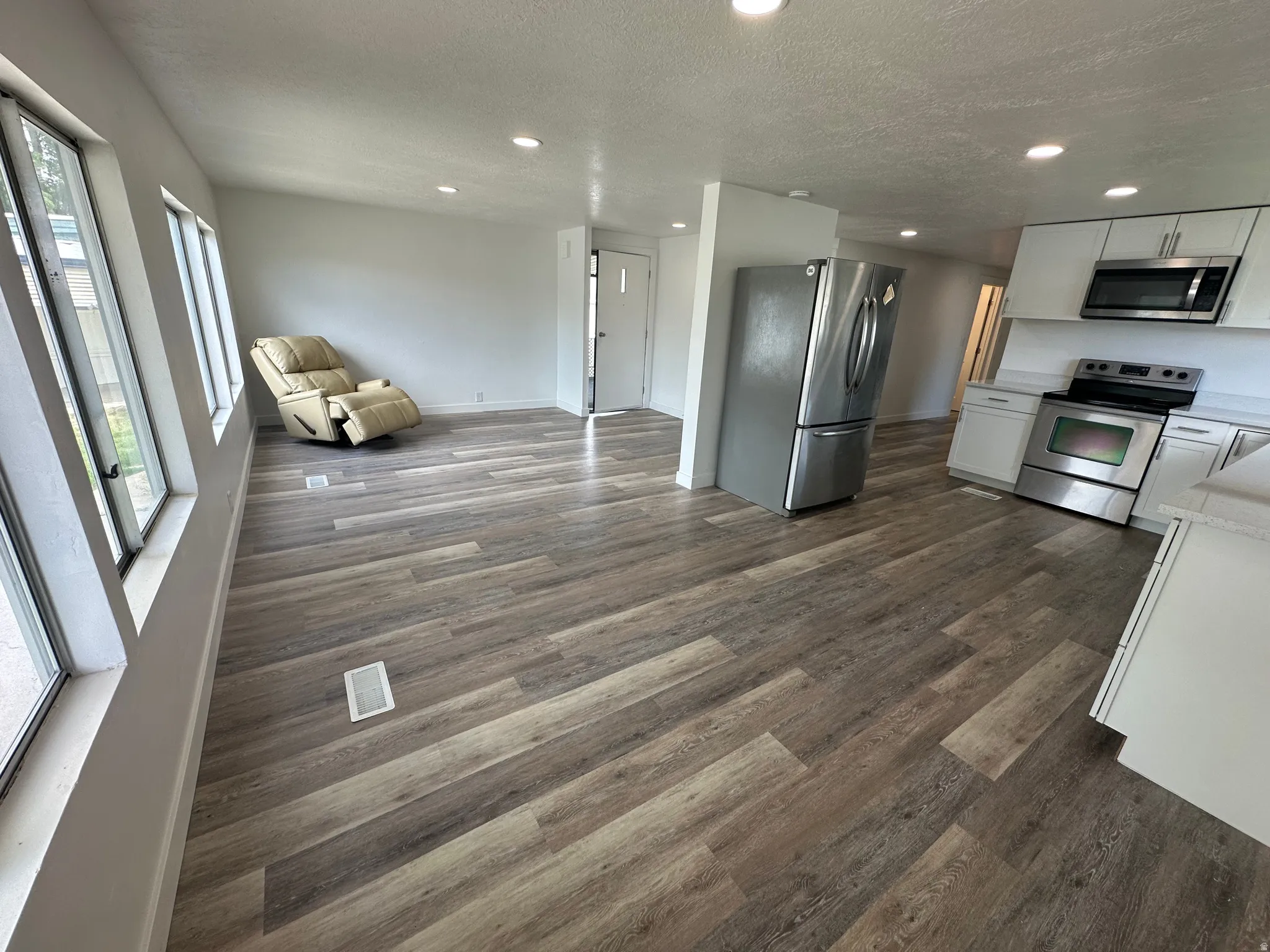 Open-concept living area featuring wood-finish flooring, recessed lighting, and large windows