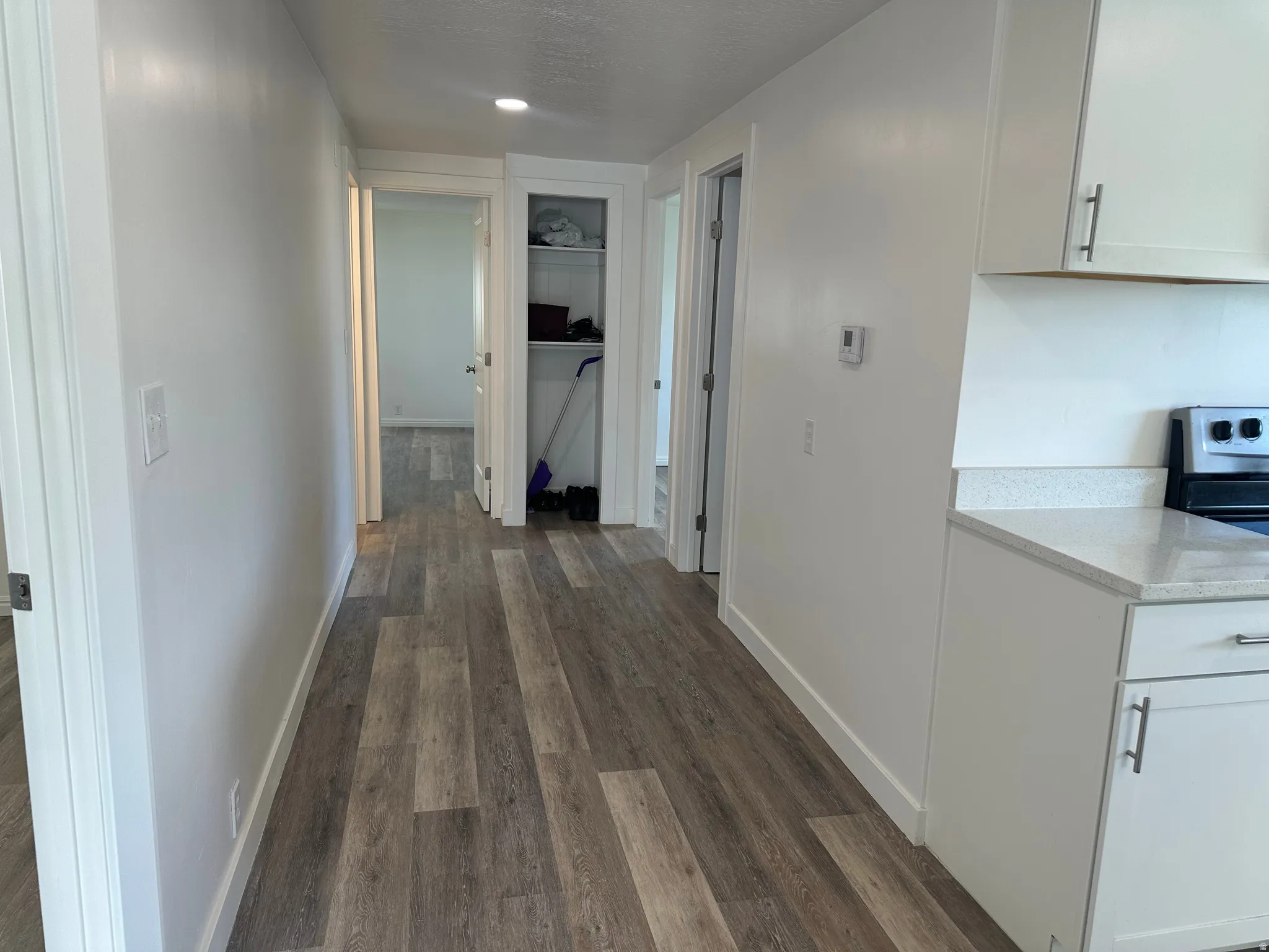 Hallway featuring wood-finish flooring and white baseboards