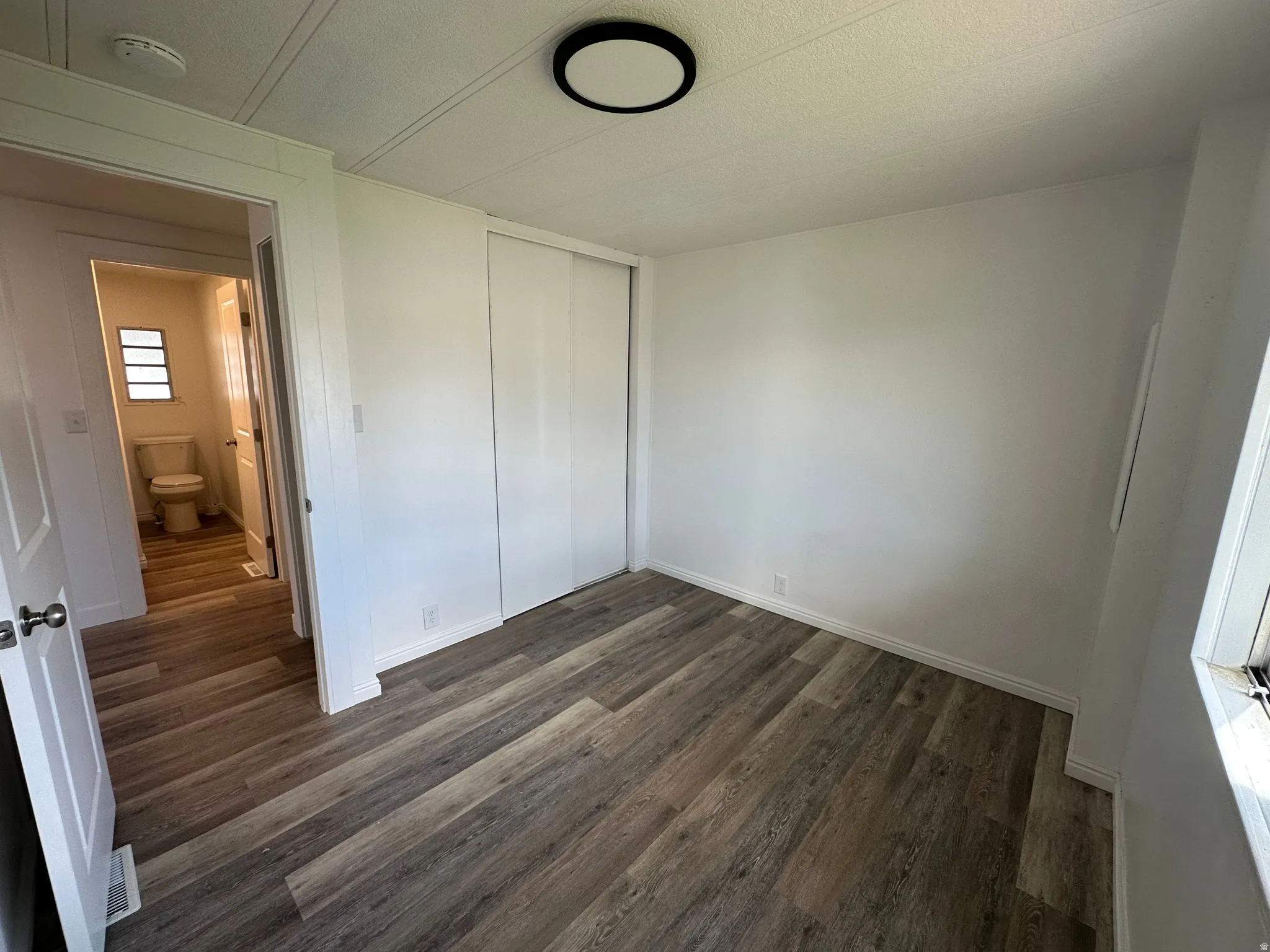 Room featuring wood-finish flooring, white walls, and a ceiling-mounted light fixture