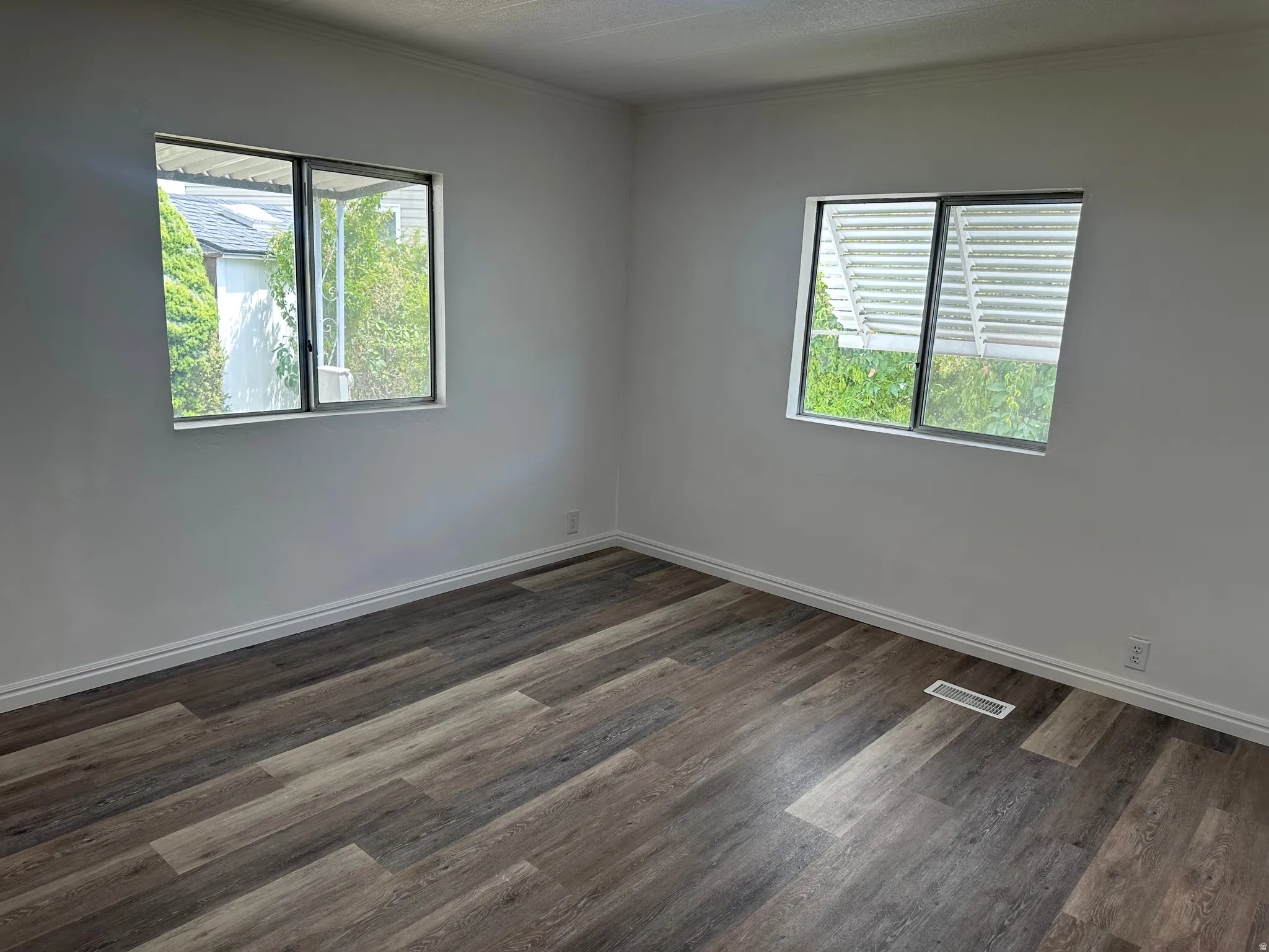 Room featuring wood-finish flooring, two windows, white baseboards, and light-toned wall paint