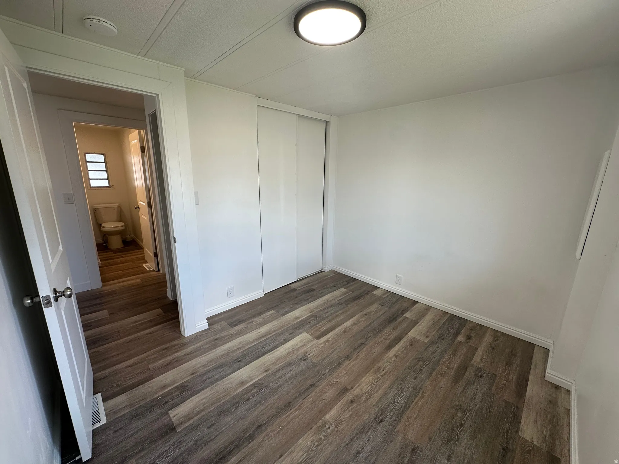 Room featuring wood-finish flooring, white baseboards, and a flush-mount ceiling light