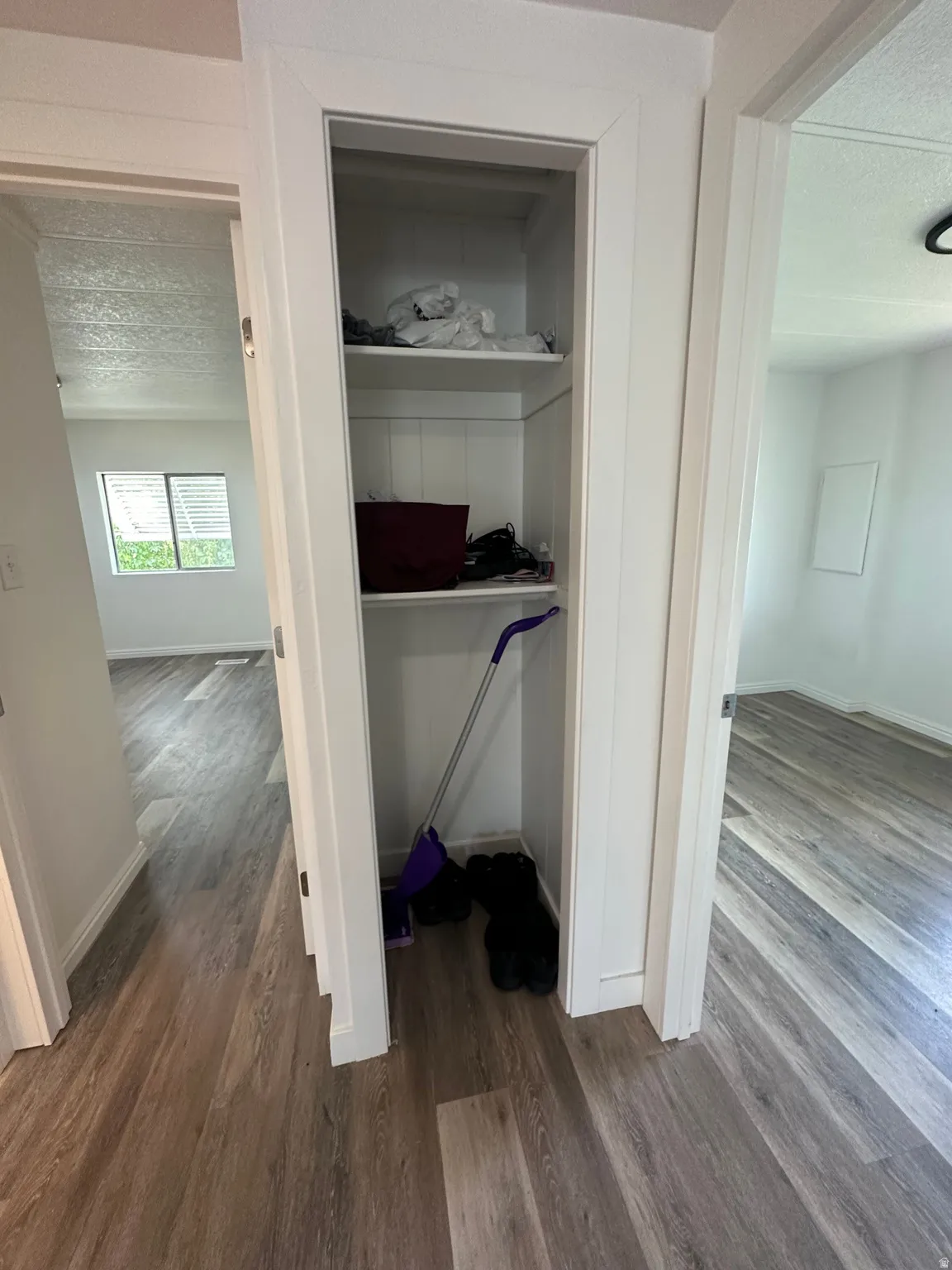 Hallway featuring wood-finish flooring, white baseboards, and a built-in storage niche with shelving